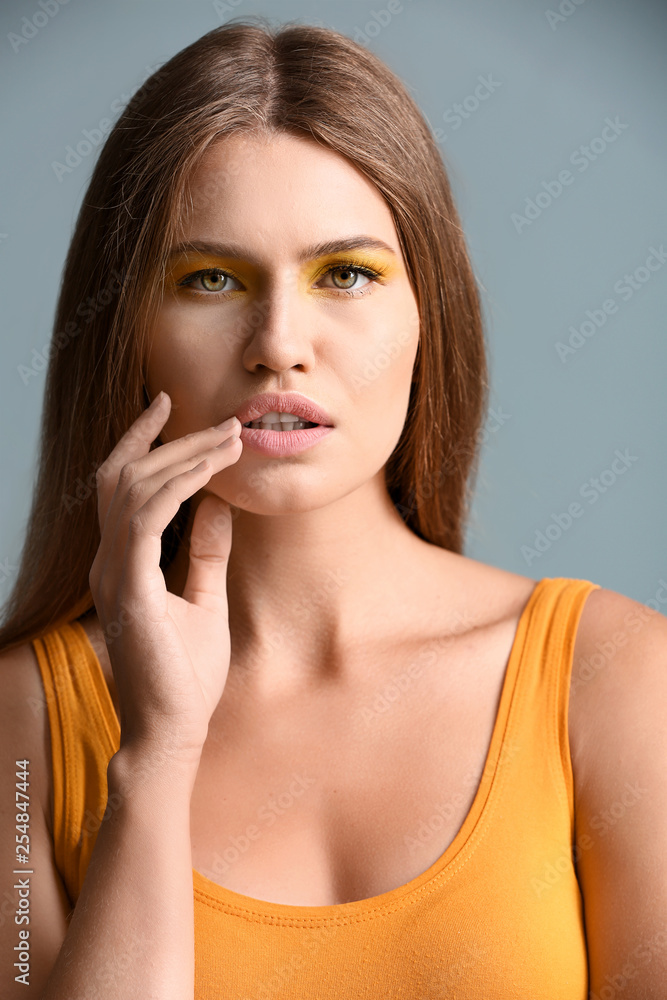 Fototapeta premium Beautiful young woman with bright makeup on color background