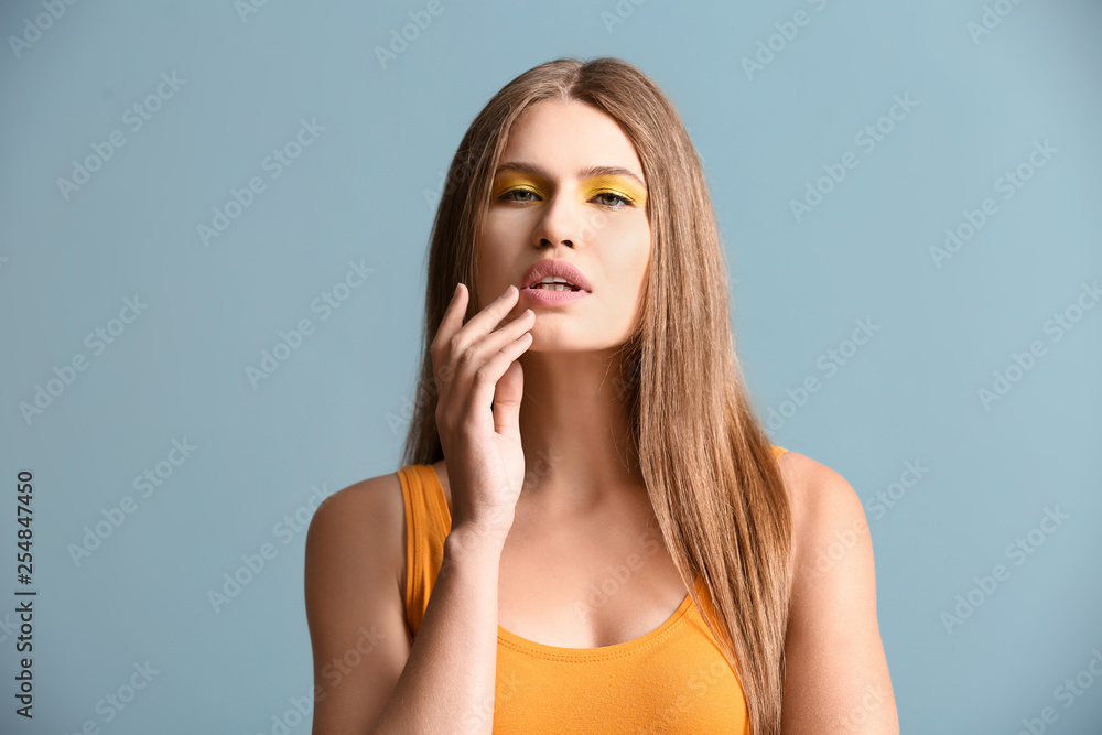 Fototapeta premium Beautiful young woman with bright makeup on color background