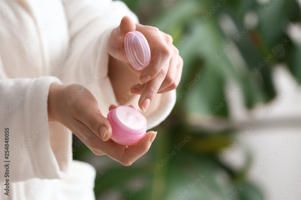 Young woman applying hand cream at home Young woman applying hand cream at home