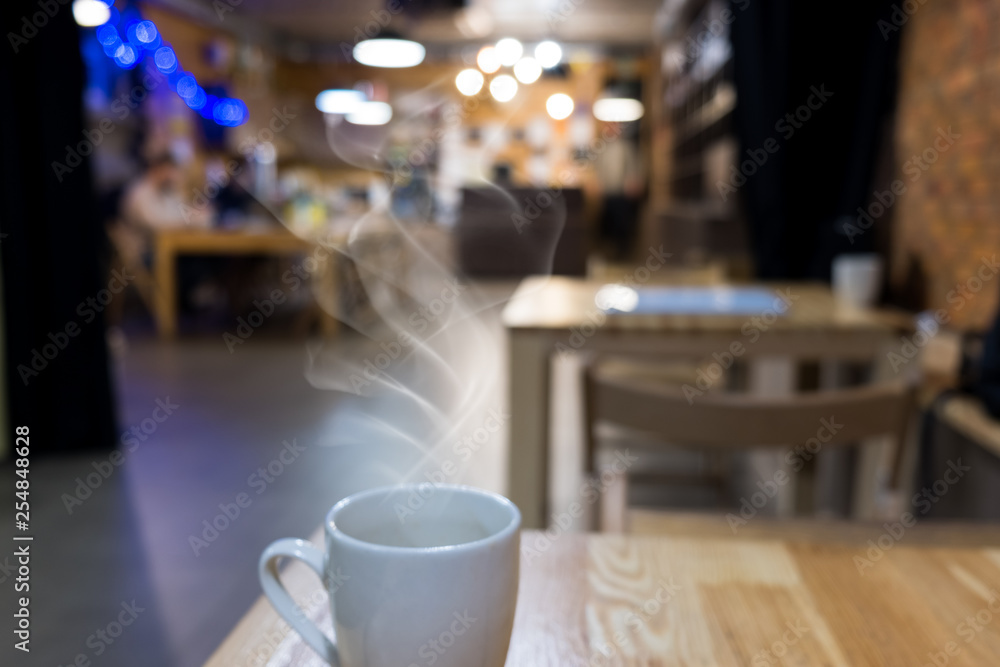 Coffee cup on wooden table in cafe interior. Abstract blurred background