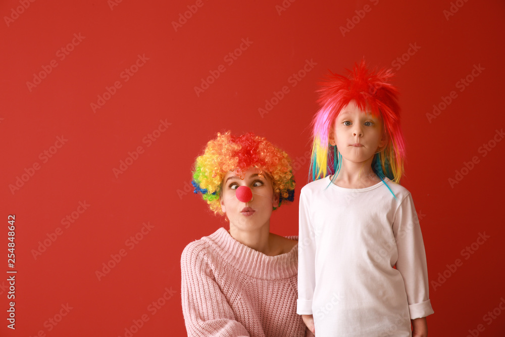 Woman and little girl in funny disguise on color background. April fools' day celebration Woman and little girl in funny disguise on color background. April fools' day celebration