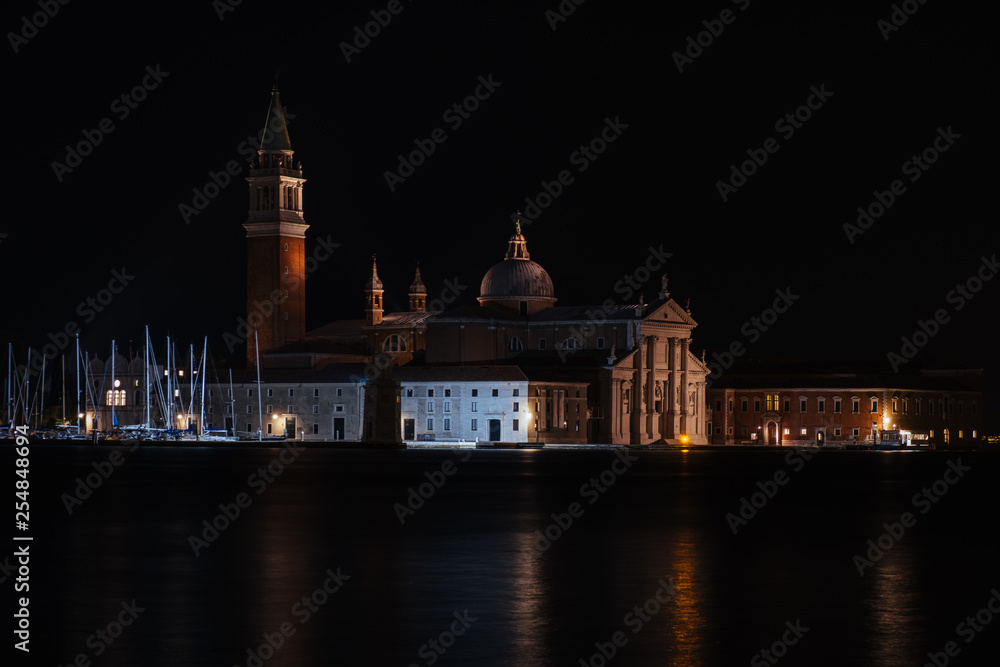 Venice canal with historical buildings and gondolas at night. Italy.
