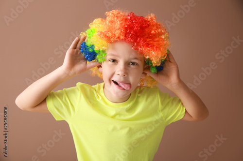 Little boy in funny disguise on color background. April fools  day celebration