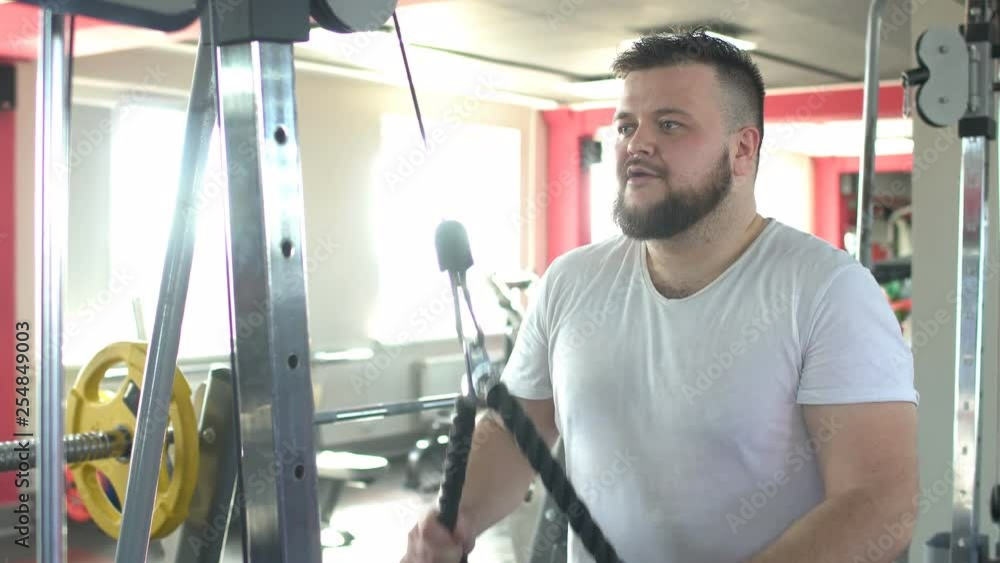 Bearded caucasian man works out in the gym with the help of the girl's individual trainer on a crossover simulator, development of the pectoral muscles Bearded caucasian man works out in the gym with the help of the girl's individual trainer on a crossover simulator, development of the pectoral muscles