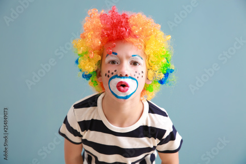 Cute little boy with clown makeup on color background. April fools' day celebration