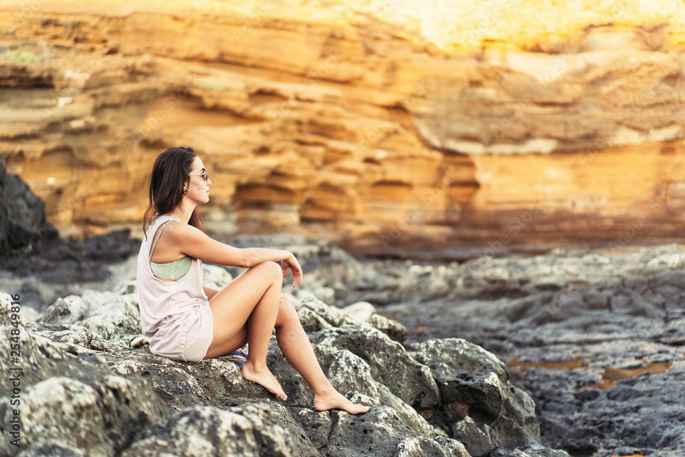 Pretty long hair brunette tourist girl relaxing on the stones near sea. Pretty long hair brunette tourist girl relaxing on the stones near sea.