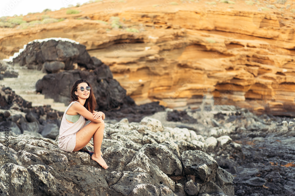 Pretty long hair brunette tourist girl relaxing on the stones near sea. Pretty long hair brunette tourist girl relaxing on the stones near sea.