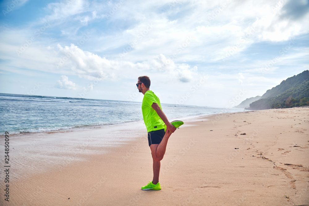 Sportsman stretching on a tropical sandy beach. Sportsman stretching on a tropical sandy beach.