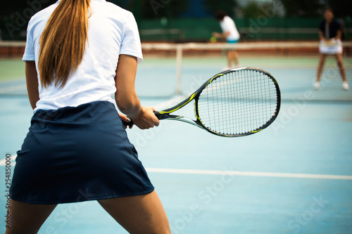 Young happy woman playing tennis at tennis court © NDABCREATIVITY