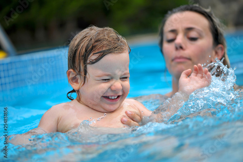 Baby plays in a pool with his Mom