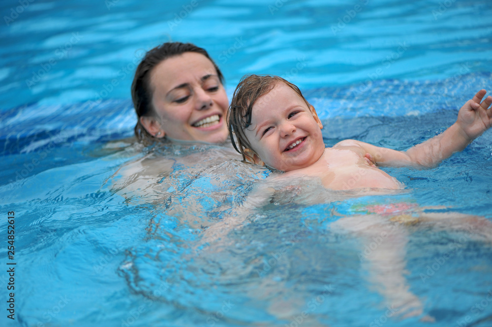 Fototapeta premium Baby plays in a pool with his Mom
