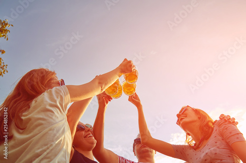 Canvas Print Group of young people enjoying and cheering beer outdoors.