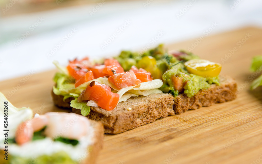 Open sandviches with guacamole, salmon and prawn on wood texture  background