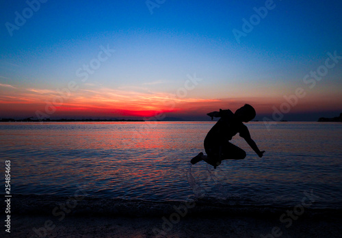Boy jumping in holiday with sunset on the beach background