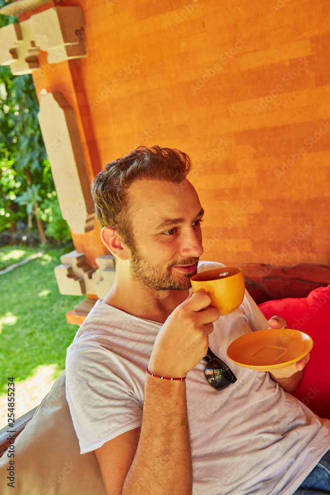 Fototapeta premium Man drinking coffee on a home porch.