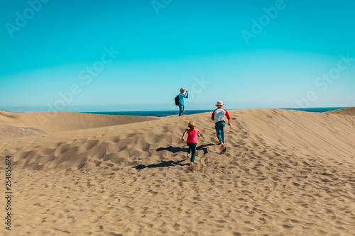 father with happy kids - son and daughter - travel in sand dunes