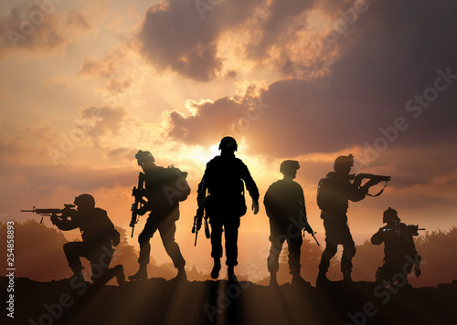 Photographie Six military silhouettes on sunset sky background