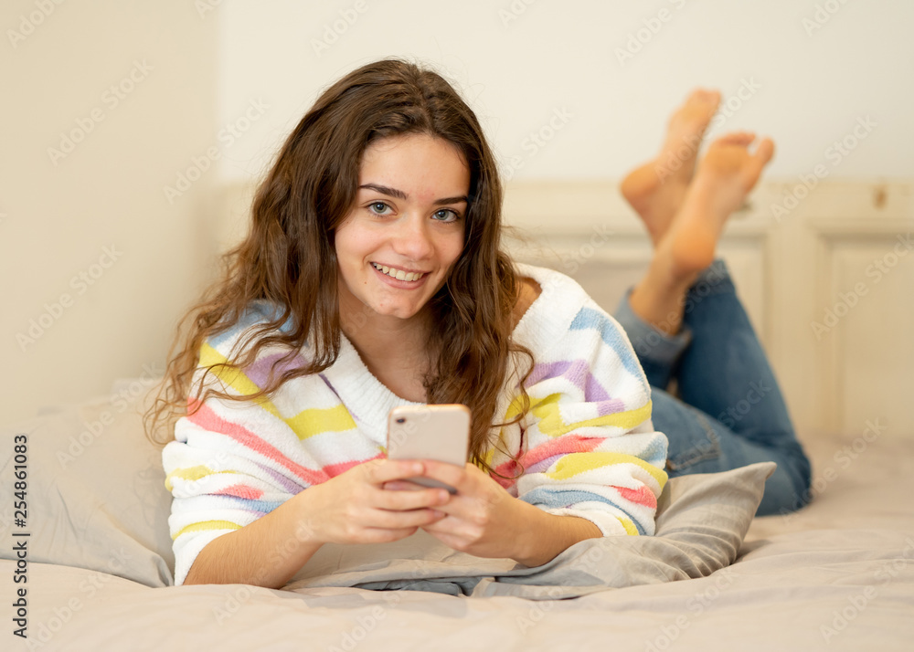 Portrait of young beautiful girl texting and chatting on her smart phone on bed Portrait of young beautiful girl texting and chatting on her smart phone on bed