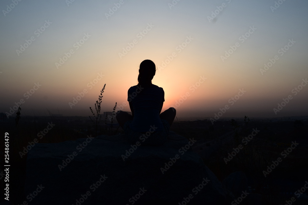 silhouette of a women meditating on the hill at sunrise