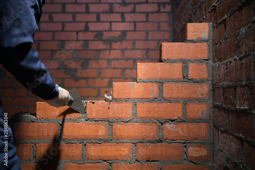 professional construction worker laying bricks and building barbecue in industrial site. Detail of hand adjusting