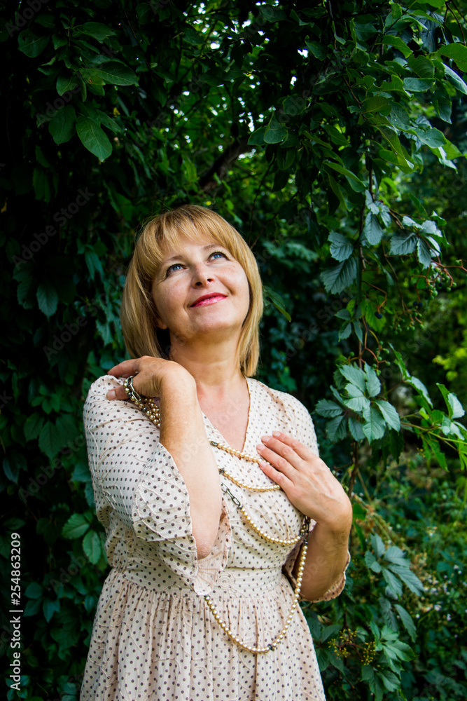 Portrait of happy beautiful blonde woman with pearls in summer park Portrait of happy beautiful blonde woman with pearls in summer park
