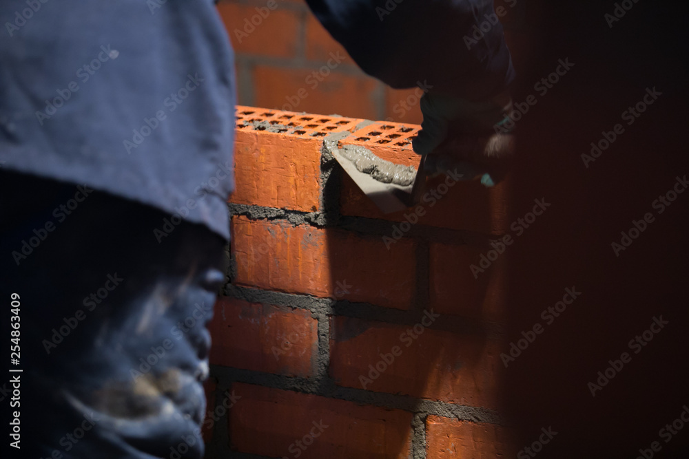 Fototapeta premium professional construction worker laying bricks and building barbecue in industrial site. Detail of hand adjusting
