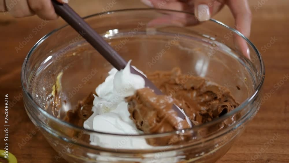 Beaten egg whites on chocolate batter. Stirring egg whites and cake batter with chocolate Beaten egg whites on chocolate batter. Stirring egg whites and cake batter with chocolate