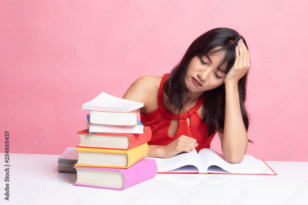 Exhausted Young Asian woman read a book with books on table.