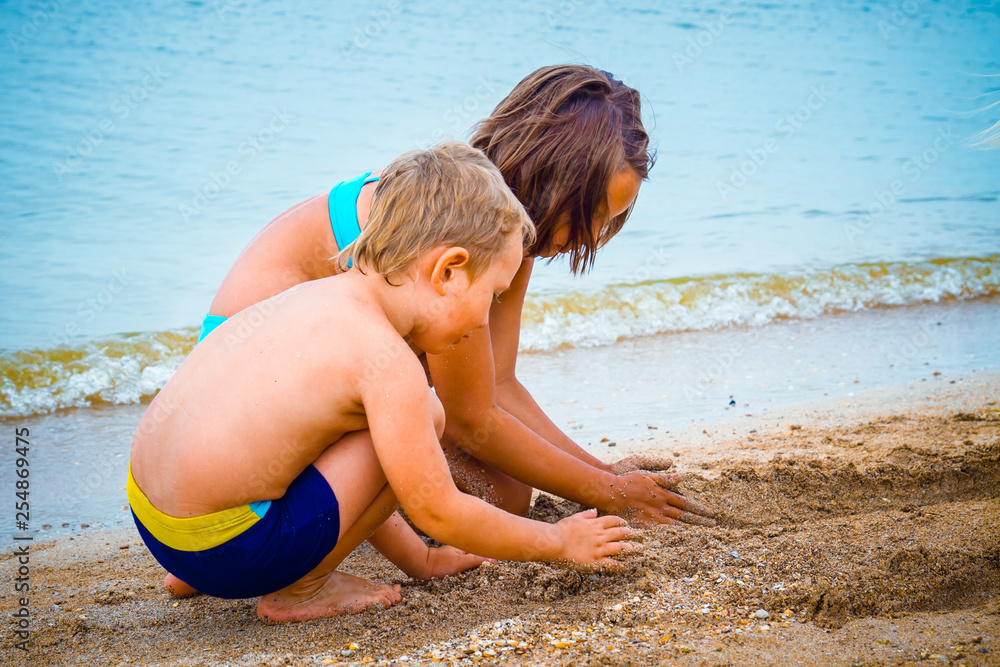 Fototapeta premium boy and girl playing on the beach with sand