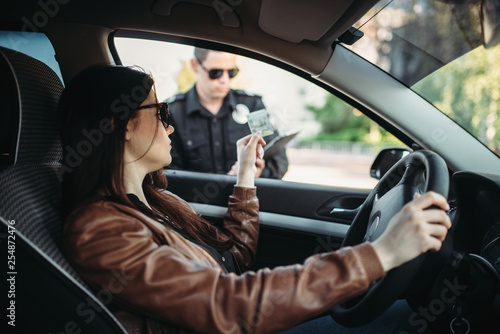 Male cop in uniform writes a fine to female driver photo