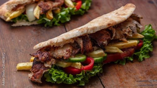 Gyros, shawarma, take away, street food. Sandwich with meat on wooden table