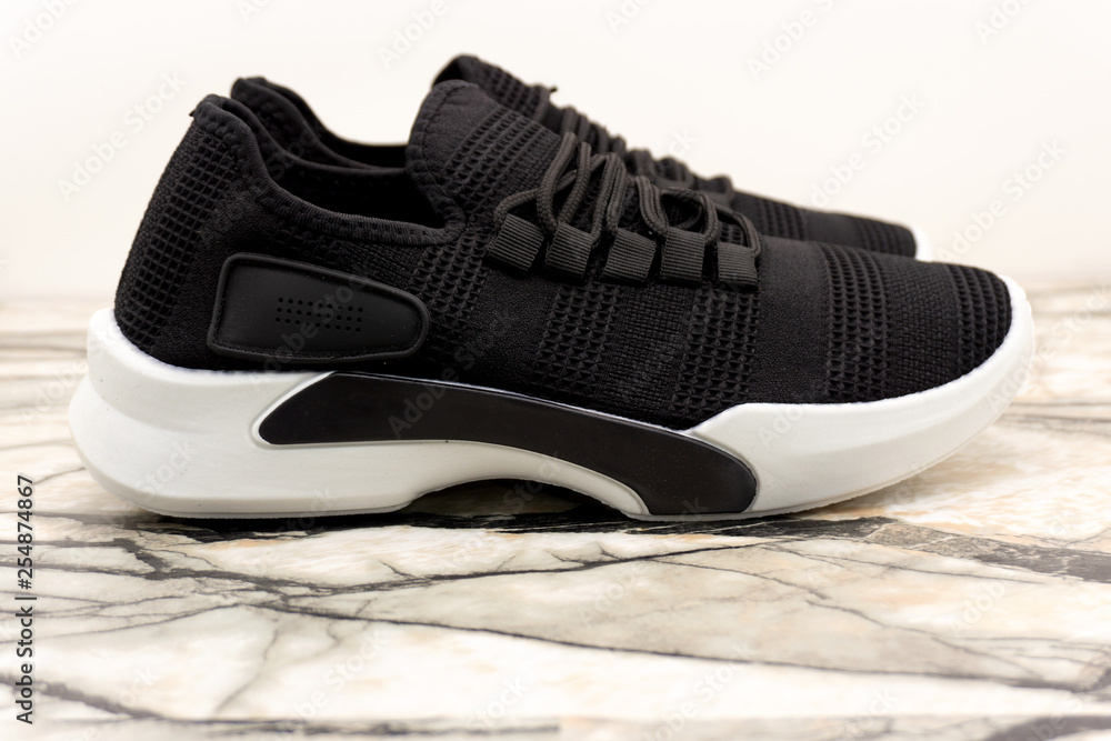 Black sport unisex sneakers with white sole and white laces on white background . Black sport unisex sneakers with white sole and white laces on white background .