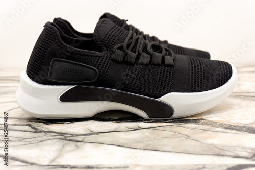 Black sport unisex sneakers with white sole and white laces on white background .