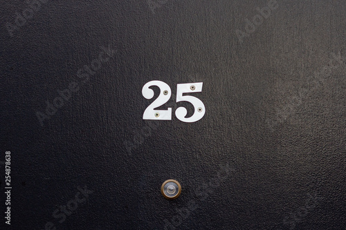 House number twenty five with the 25 in silver on a black door with peephole