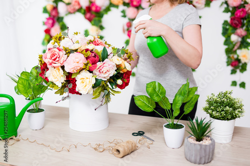 female florist or gardener watering flowers in flower shop