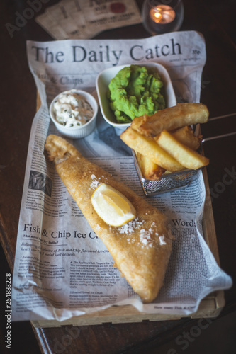 Photography Fish, chips, mushy oeas and tartar sauce on newspaper