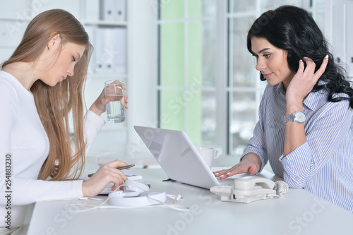 Portrait of two young women working at office with laptop