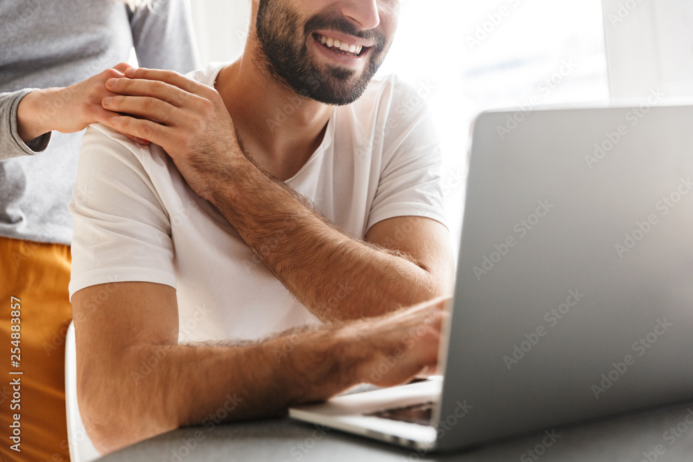 Amazing happy young loving couple sitting at the kitchen using laptop computer. Amazing happy young loving couple sitting at the kitchen using laptop computer.