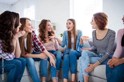 Portrait of her she nice girlish lovely attractive pretty cheerful cheery talkative ladies sitting on divan having fun talking discussing rumour get-together in light white interior room indoors