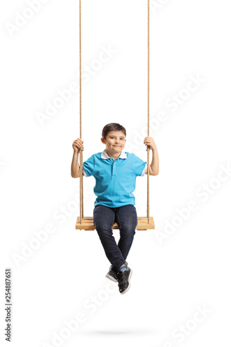 Happy little boy sitting on a swing and looking at the camera