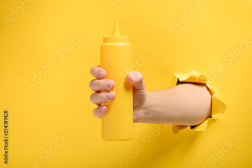 Hand holding a mustard bottle