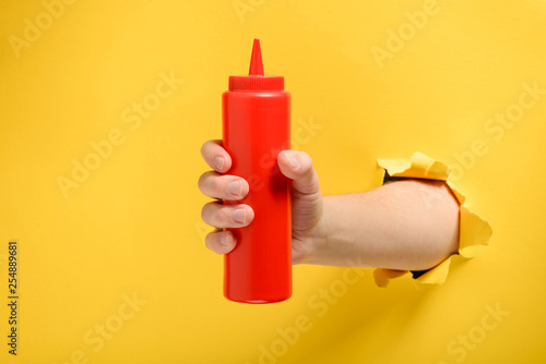 Hand taking a ketchup bottle