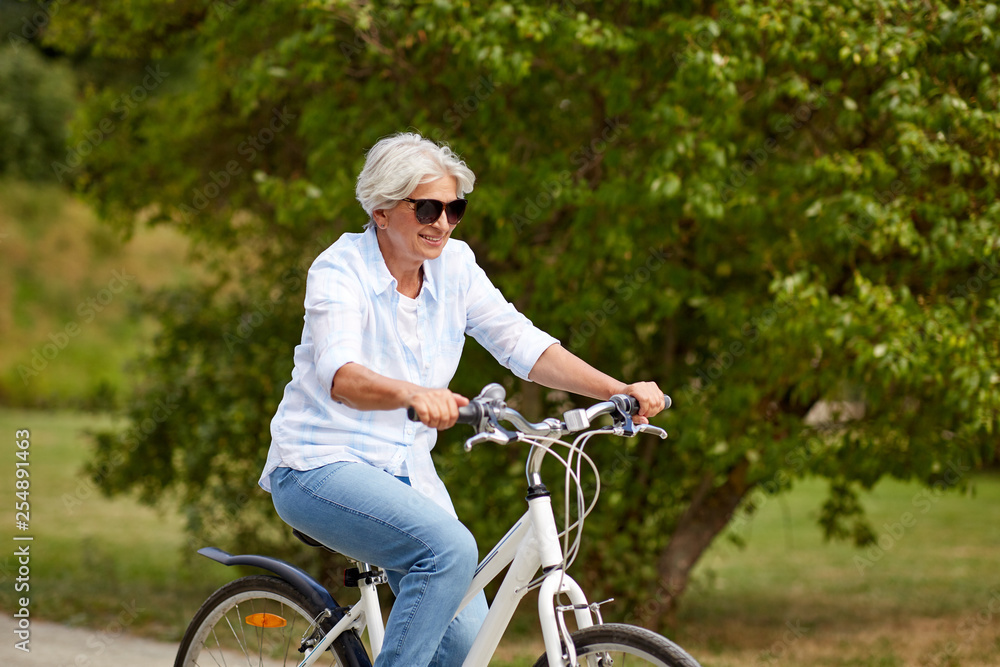 active old age, people and lifestyle concept - happy senior woman riding fixie bicycle at summer park active old age, people and lifestyle concept - happy senior woman riding fixie bicycle at summer park