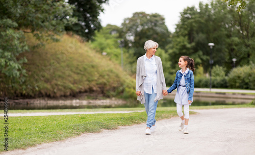 family, leisure and people concept - happy grandmother and granddaughter walking at summer park © Syda Productions