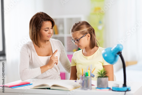 education, family and learning concept - strict mother talking to daughter while doing homework at home