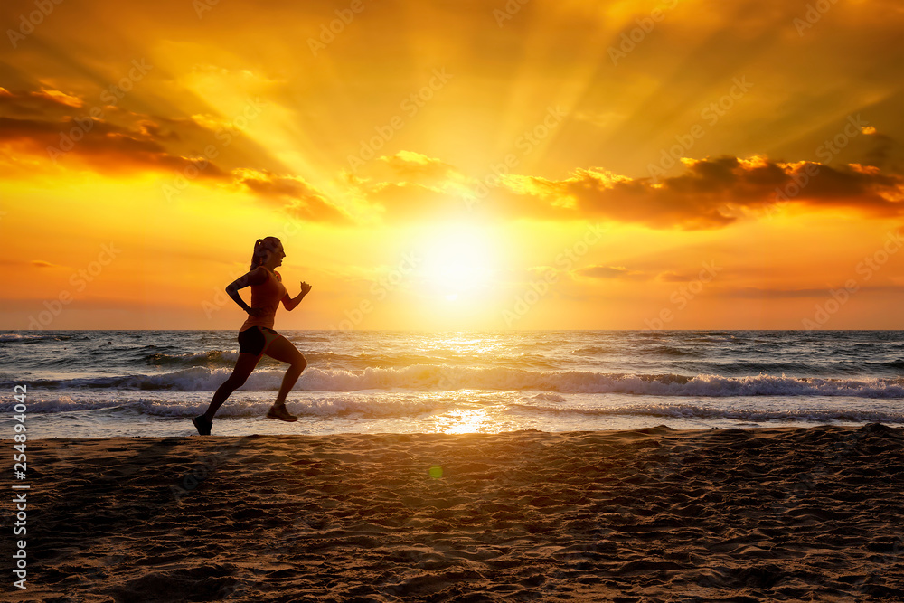 Silhouette einer laufenden Frau bei Sonnenuntergang am Strand während ihres Trainings