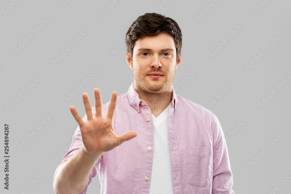 count and people concept - young man showing five fingers over grey background count and people concept - young man showing five fingers over grey background