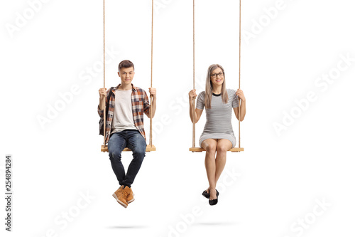 Teenage male student and a young woman sitting on a swing