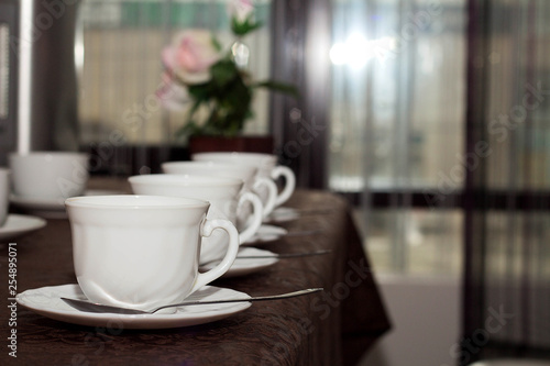 white cups of tea are in a row on the table with a brown tablecloth