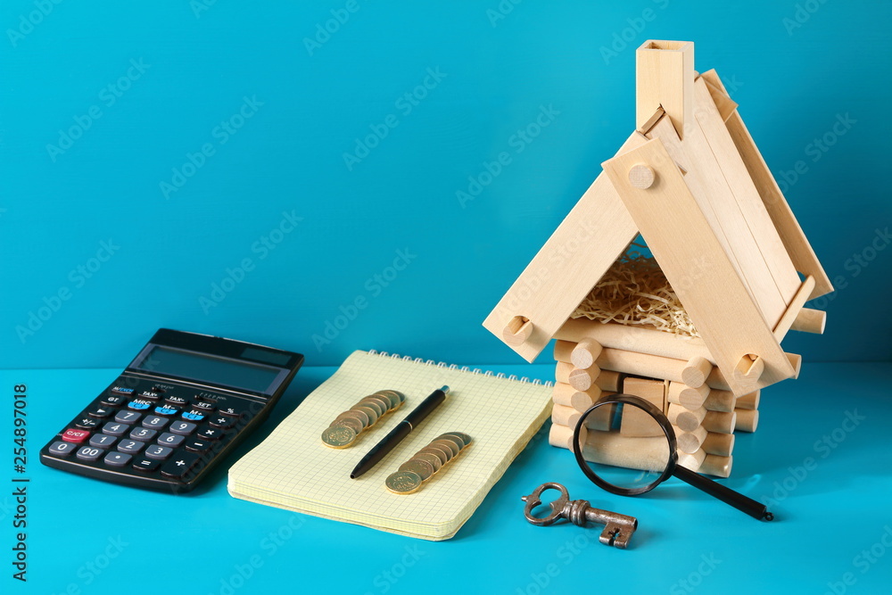 Fototapeta premium Model of log house and an iron key on the wooden background. Business concept.